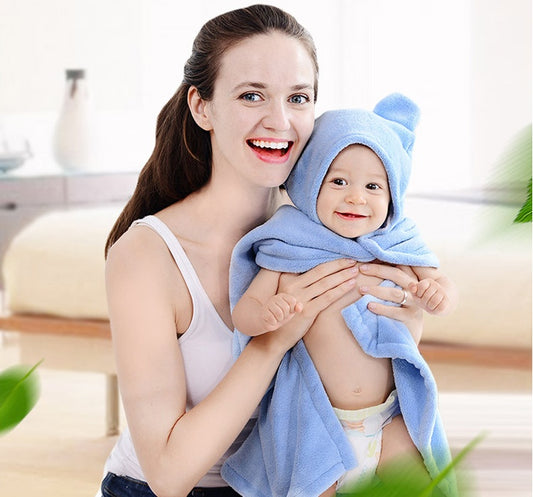 Mother holding a smiling baby wrapped in a blue hooded towel
